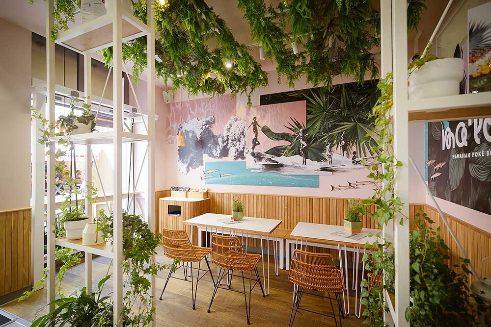 Tischgruppen vor bunt gestalteten Wänden im Hawaiianischen Stil mit vielen Farben und Pflanzen